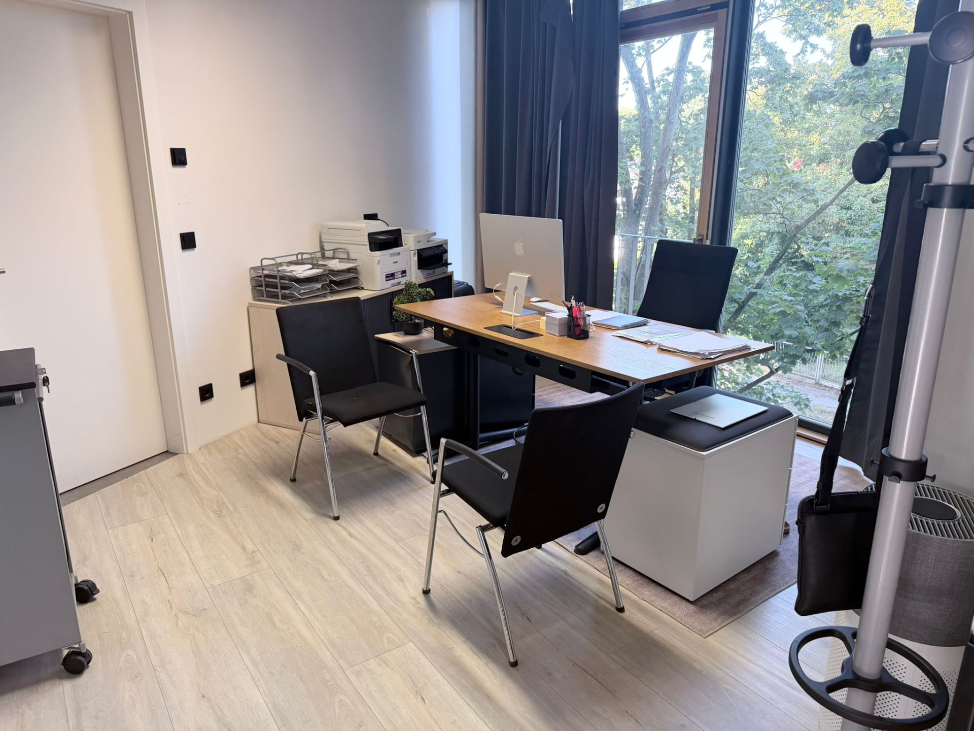 Arbeitsplatz mit Schreibtisch, Drucker und großem Fenster
