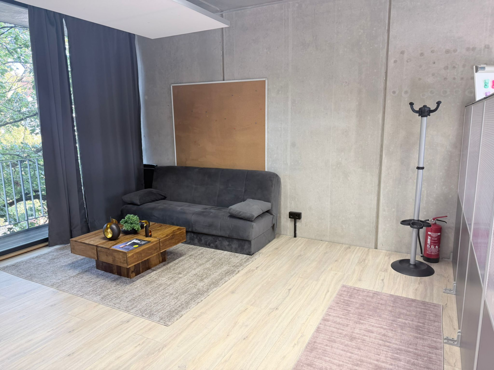 Wartebereich mit Sofa vor Sichtbetonwand